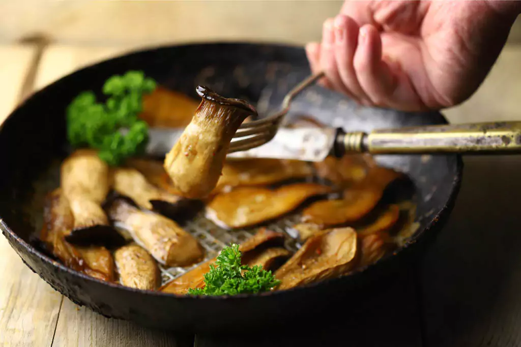 Gourmet mushroom recipes being cooked in a black pan.